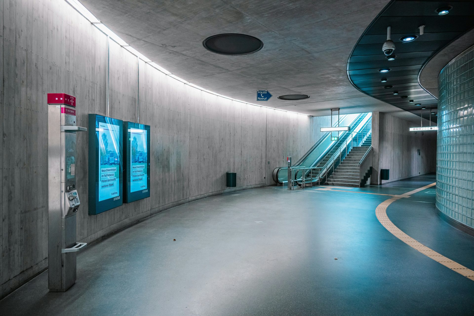 Modern subway station with escalators and digital displays.